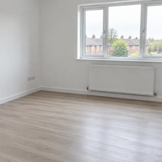 An empty room in a rented flat with laminate flooring and a bare window