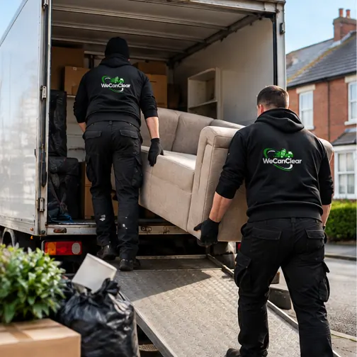 Two staff carrying a sofa into the back of the van